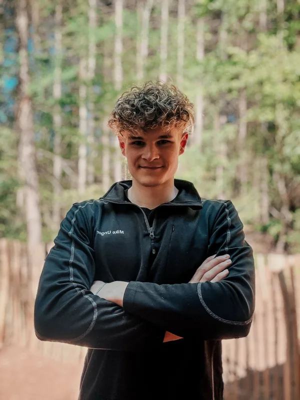 Mike mit verschränkten Armen im Wald